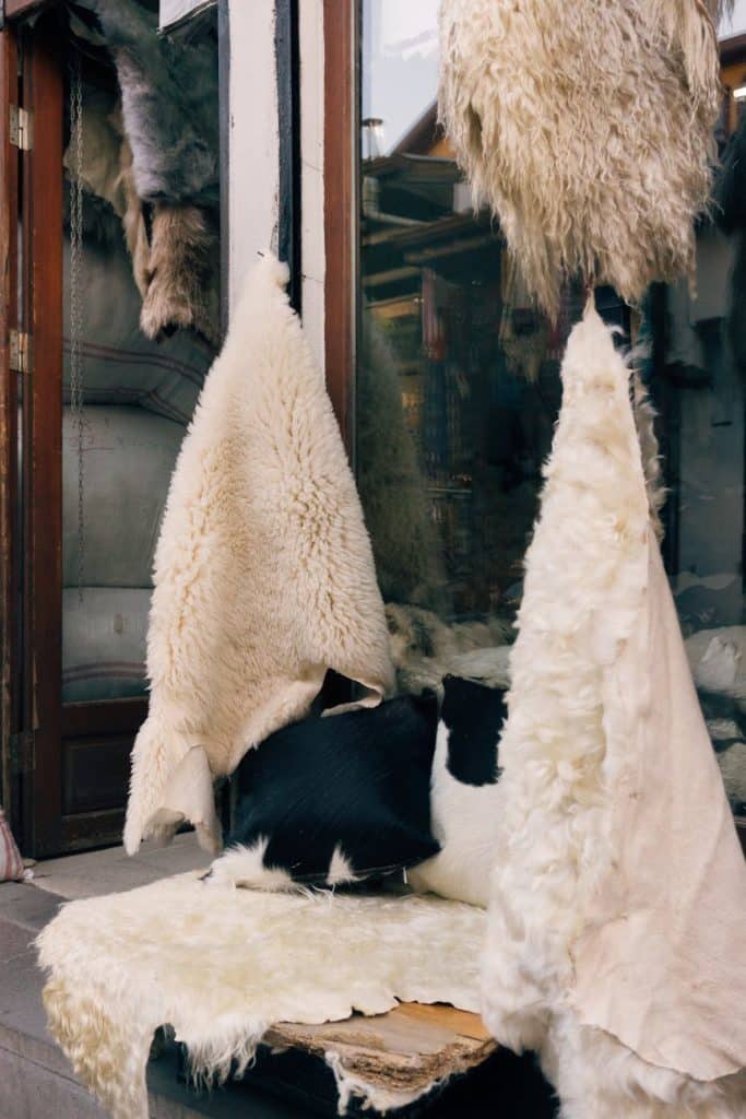 Cozy sheepskin rugs showcased outside a market shop, exuding warmth and texture.