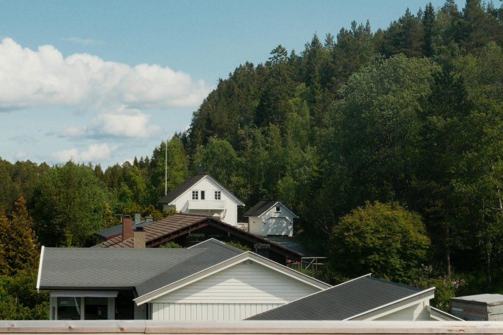 Tranquil view of countryside homes nestled in lush forest under a clear blue sky.