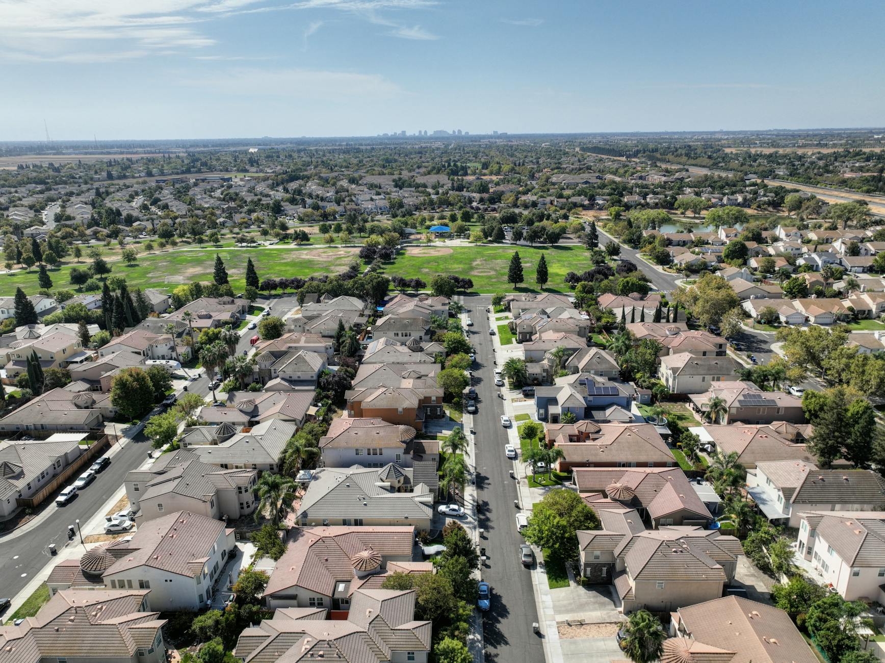 Scenic aerial view of Sacramento suburb with rows of houses and lush greenery on a sunny day.