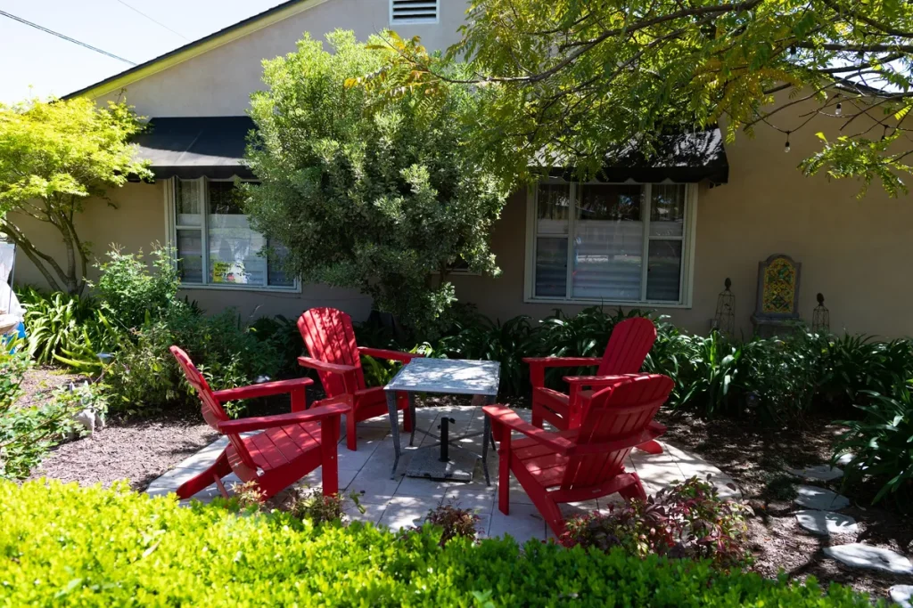 A backyard with red adirondack chairs and a table, highlighting outdoor living in West Grey real estate.